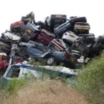 A bidder reviews paperwork and a tablet beside rows of used cars at a Copart auction lot.