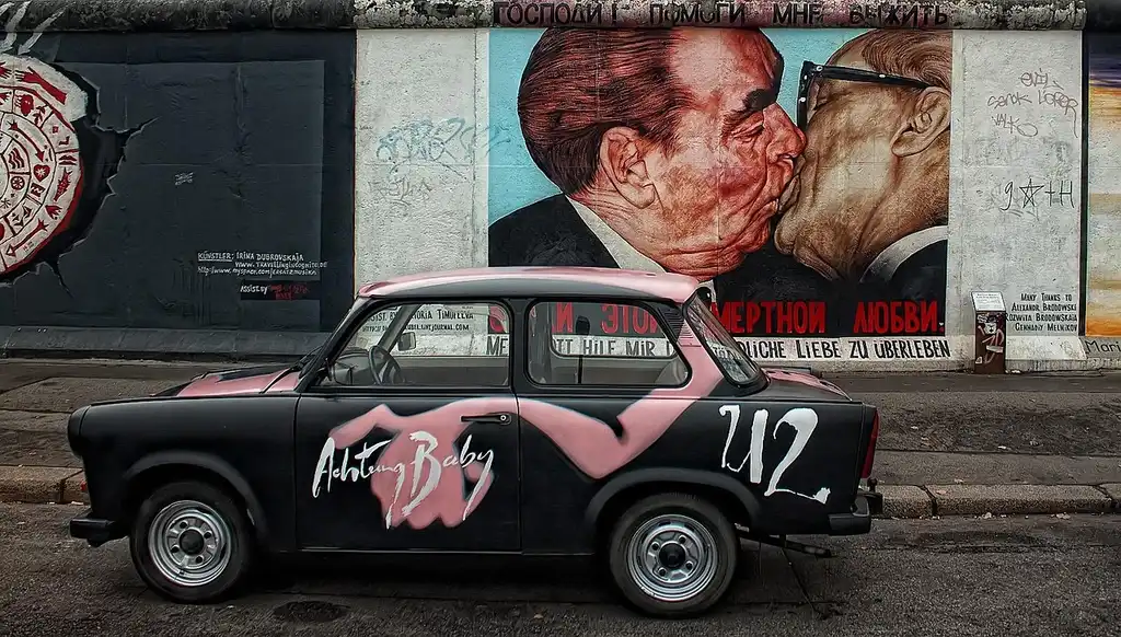 Seller and auction buyer reviewing paperwork next to a used sedan at an auction lot