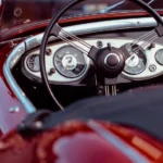Seller reviews an online car auction payout statement beside keys, paperwork, and a laptop.