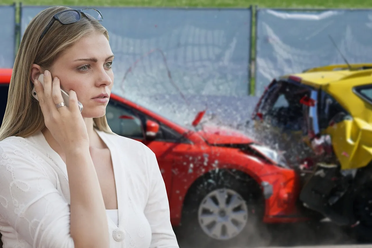 Auction buyer reviewing a vehicle history report beside a used sedan at an outdoor auction