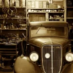 Repaired sedan in an inspection bay with a mechanic and inspector reviewing post-repair condition.