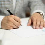 Seller and auction representative review a car auction consignment agreement beside keys and paperwork.