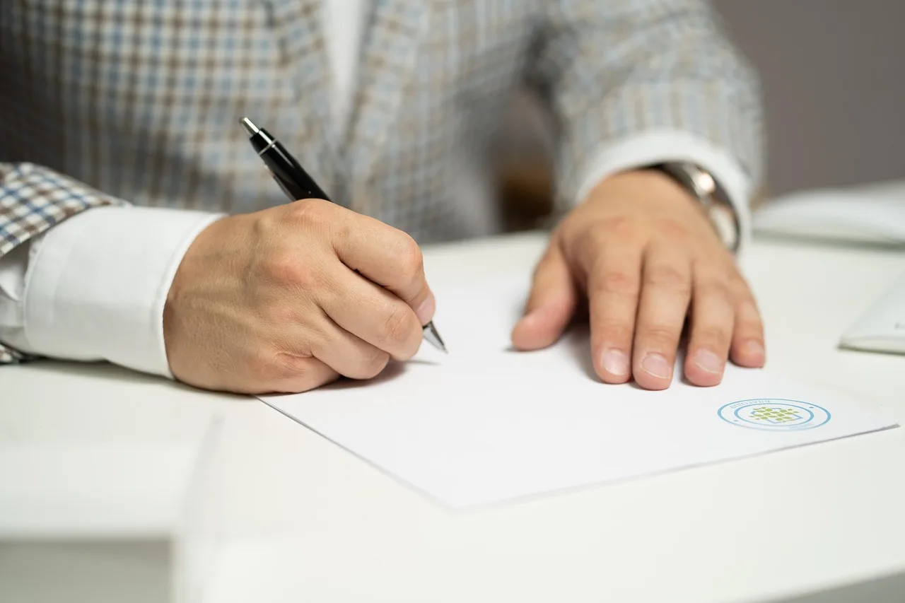 Seller and auction representative review a car auction consignment agreement beside keys and paperwork.