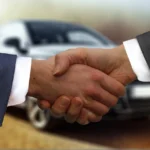 A dealer reviewing used cars on a lot, weighing wholesale vs retail dealer license options.